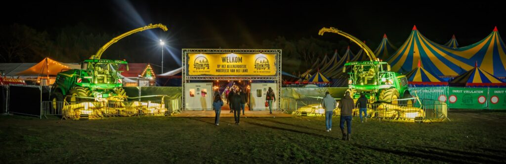 De ingang van After Maïs met verlichte landbouwmachines en feesttenten