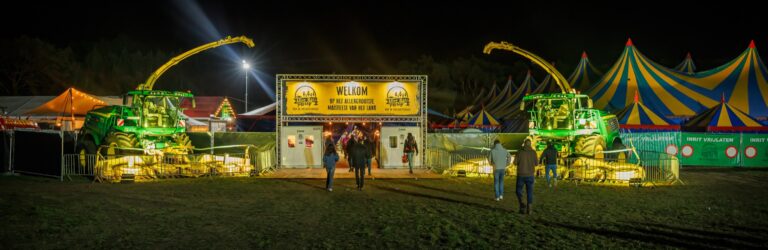 De ingang van After Maïs met verlichte landbouwmachines en feesttenten